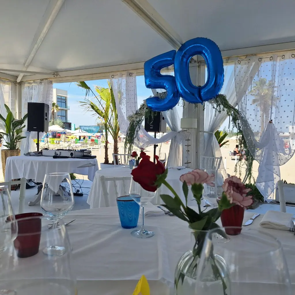 Allestimento per un cinquantesimo in spiaggia con palloni 50 e postazione DJ